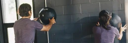 Undenied Fitness People Throwing Medicine Ball against a Wall